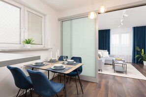 A dining area featuring a glass table and blue chairs, complemented by natural light.
