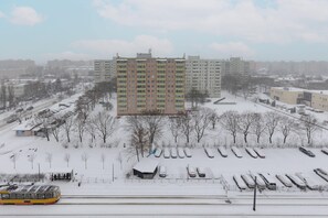 A snowy view of a residential area, with a tall building in the background.
