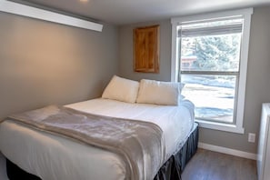 The guest bedroom is flooded with natural light from the large window looking out towards the front of the home and features a queen size bed, closet space, a stacked washer/dryer, and a full bathroom connected with a jack-and-jill door.