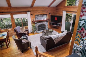 Cozy by the wood stove, enjoy a 55" smart TV, with skylights and sliding doors to the side deck.