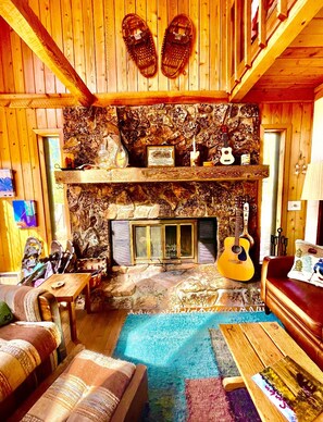 Living room with open loft above.  Fireplace, guitar, ukelele and mandolin.