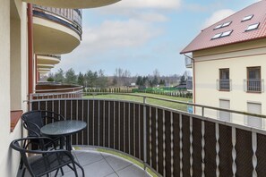 A spacious balcony offers a view of the surrounding buildings. There is a small outdoor seating area with a table and two chairs, perfect for enjoying fresh air.