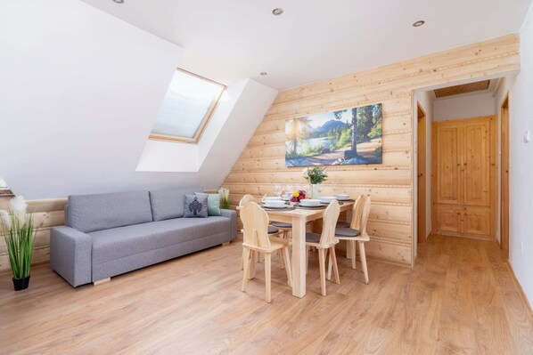 A cozy attic-style living area with wooden paneling and a dining table.
