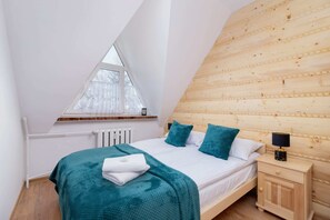 A bright bedroom with teal bedding and triangular windows for a mountain view.
