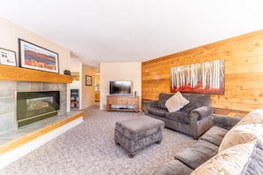 Living area with flat screen TV, gas fireplace, ample seating and queen sleeper sofa.