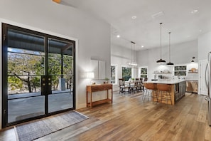 As you walk back out of the bedroom hallway you enter the living area again.  The doors the the back deck can be seen as well as the kitchen and dining areas.