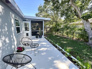 Charming patio with sitting area, Webber grill, palm trees and greenery. 