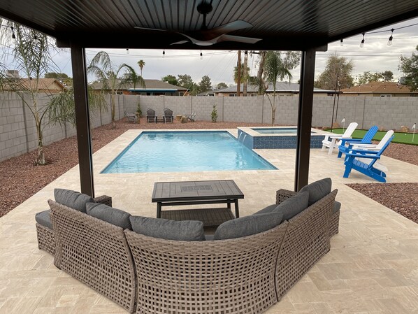 Pergola with patio furniture and table, along with fan viewing pool 