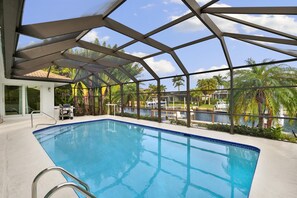 Screened and heated pool with canal view.