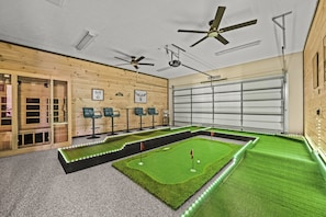 The room's sleek wooden panels and bright green turf enhance the experience High-top bar stools for those watching the game or waiting their turn