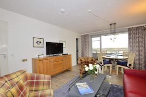 Wohnzimmer mit Sofa, Sessel, Essplatz und TV