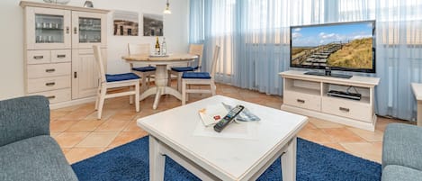 Wohnzimmer mit Sofa, TV und Essplatz