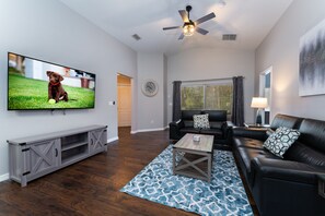 Open floor plan showing sofa and loveseat with wall-mounted Smart TV