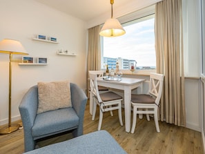 Wohnzimmer mit Sessel und Essplatz am Fenster