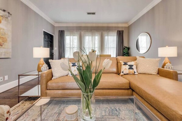 Bright open living room featuring a leather chaise sofa and a stylish green velvet chair, blending comfort and elegance.