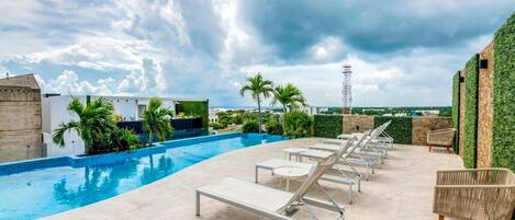 The rooftop has an amazing pool and lounge chairs with a city skyline view