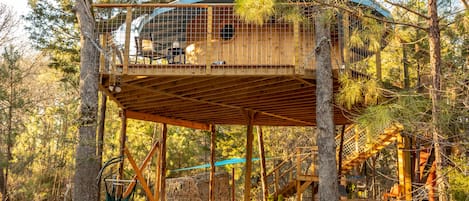 Living area features hanging chairs, firepit, picnic table, and kitchen set