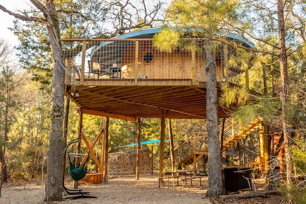 Living area features hanging chairs, firepit, picnic table, and kitchen set