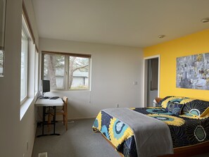 The master bedroom has a queen bed, water views, a retro bed frame & work table.