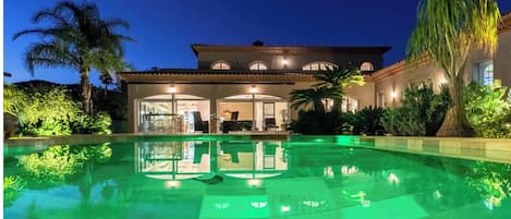 Vista nocturna de la Villa con su iluminación automática y su piscina.

