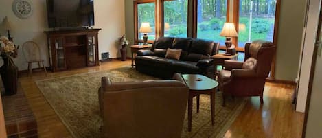 Living room with lots of natural light, 70” Smart TV and comfy leather furniture. 