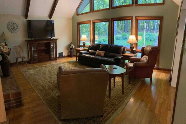 Living room with lots of natural light, 70” Smart TV and comfy leather furniture. 