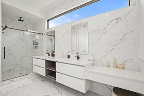 All marble master bathroom with dual sinks, vanity area, waterfall shower and bathtub