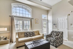 Two story living room with doors to deck.  Ottoman coverts to a single bed.