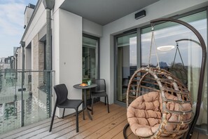 A balcony with comfortable hanging chairs and a glass railing offering scenic views.
