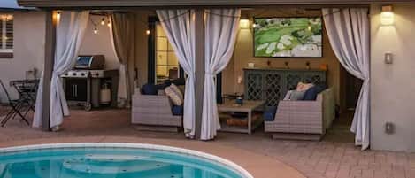 Outdoor living space with 65" TV, BBQ, Patio seating and pool bath.