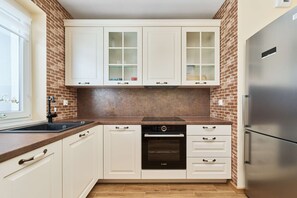 A kitchen with white cabinets, a modern fridge, and exposed brick accents for a rustic touch.