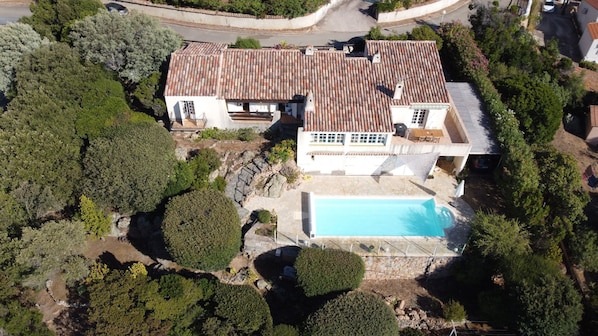 La maison, sa terrasse, sa piscine, son carport et son jardin vue de drone..