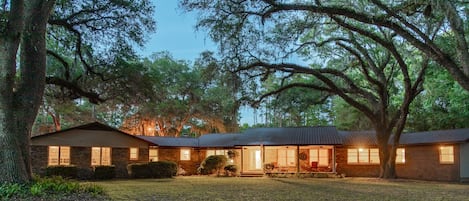 Large home under a canopy of old oak trees.