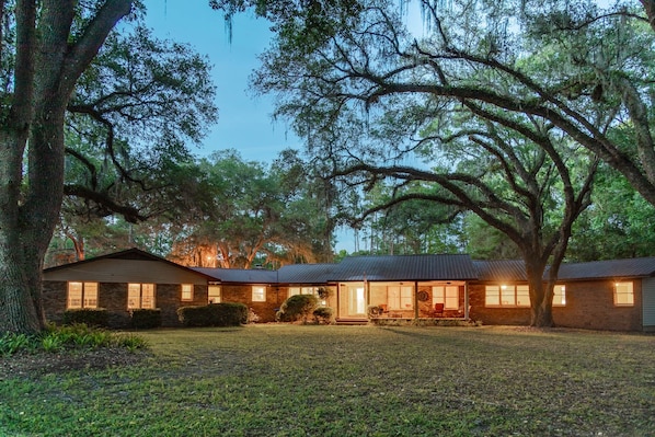 Large home under a canopy of old oak trees.