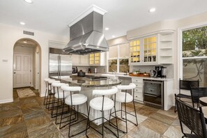 A spacious chef's kitchen with a large island and bar stools.