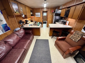 Living area with full-sized couch, recliner, & 2 bar stools. 