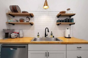 Kitchen with butcher block countertops, backsplash and cute shelving. 