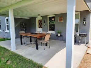 Open front porch with table, chairs and small charcoal grill. 