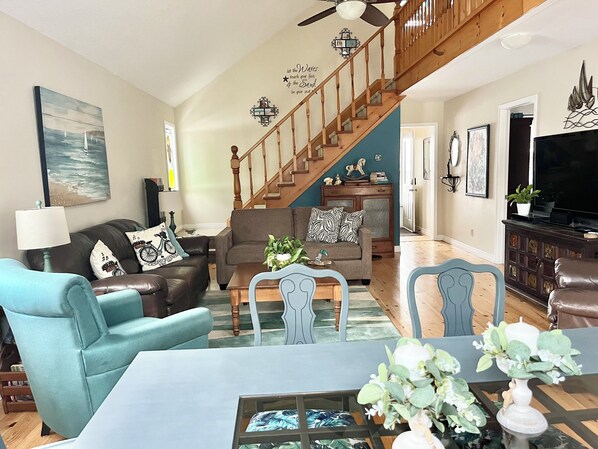 Open concept great room with lots of seating, large dining table, and sofa bed
