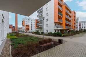 Outdoor view of the building showcasing a vibrant, modern apartment complex with green spaces and walkways.

