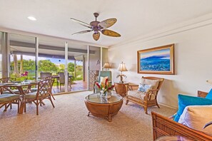 This spacious open-concept living room connects seamlessly to the outdoor lanai, creating the perfect setting for indoor-outdoor living with panoramic tropical views and a relaxed ambiance.