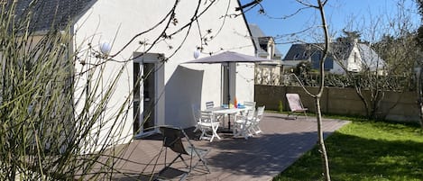 Terrasse au sud avec sa pelouse et ses arbustes.