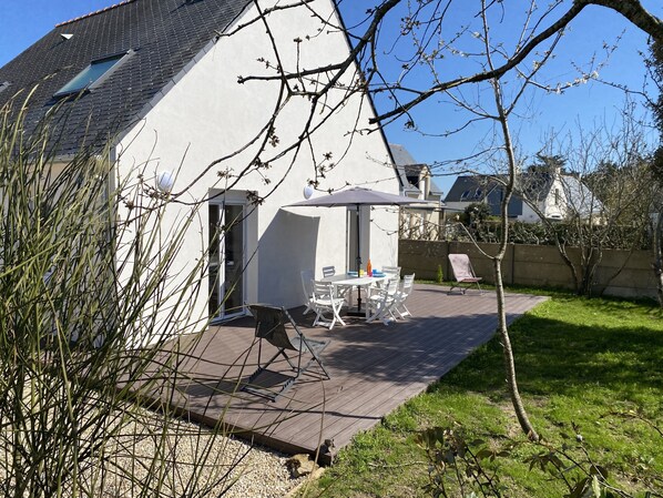 Terrasse au sud avec sa pelouse et ses arbustes.