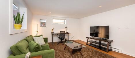 Stylish living room with great couch, 55" TV, and adjustable standing desk.