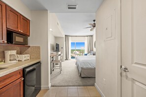 View from entryway: kitchenette, bathroom door, king bed, tv, table/chairs