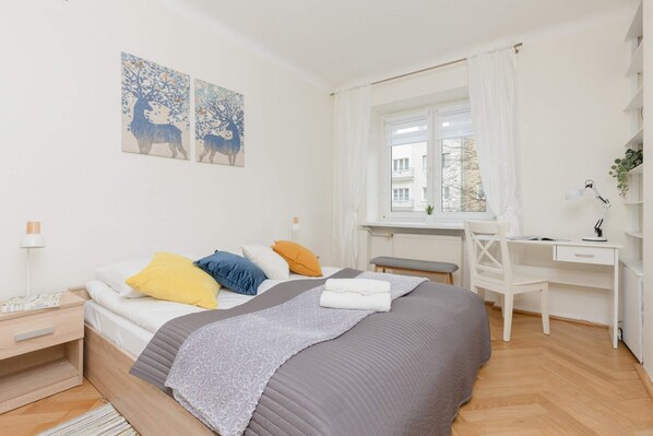 Bright bedroom with a comfortable bed, soft linens, and a desk by the window for work or relaxation.

