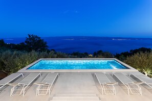 Pool area with sunchairs and outdoor shower.