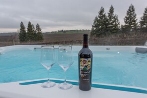 Hot tub overlooks a vineyard and the Sierra mountain range in the distance.
