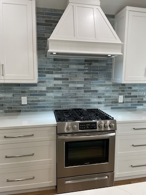 Gas stove, custom made vent and cabinets and beautiful backsplash. 