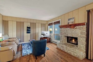 Enjoy the perfect living space with three inviting chairs, a Smart TV, a warm indoor gas fireplace, direct access to an outdoor deck, and the convenience of a window AC unit.